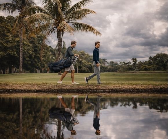 Homens com estilo smart casual masculino caminhando lado a lado, usando roupas elegantes e confortáveis em um cenário ao ar livre com árvores e um lago.