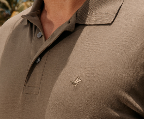 Homem usando uma polo em tom neutro, ideal para se vestir bem no calor, com tecido leve e confortável perfeito para dias quentes.