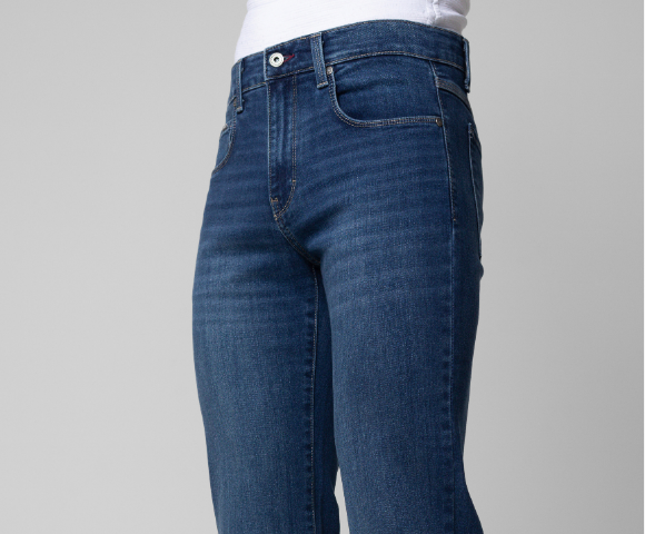 Calça jeans masculina azul, vista traseira, com costuras aparentes, cós com passantes e botão metálico na cintura.